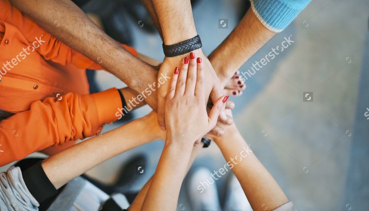 stock-photo-closeup-of-stack-of-hands-young-college-students-putting-their-hands-on-top-of-each-other-190131125